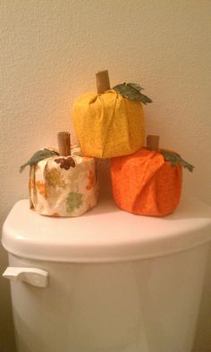 three toilet paper pumpkins sitting on top of a toilet