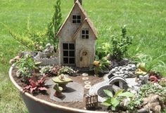 a fairy garden is in the middle of a potted planter with a house on it