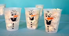 four frosty cups with faces drawn on them, all decorated to look like snowmen