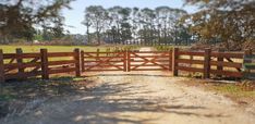 a wooden gate in the middle of a dirt road