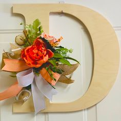 a wooden letter decorated with flowers and ribbons