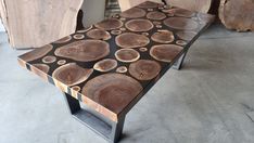 a wooden bench sitting on top of a cement floor next to wood slabs and logs