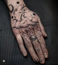 a person's hand with tattoos on it and clouds in the sky above them