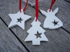 three wooden ornaments with red and white ribbons hanging from them on a wood table top