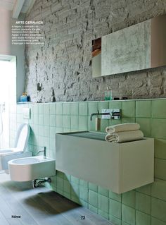 a white sink sitting next to a toilet under a bathroom mirror in a green tiled room