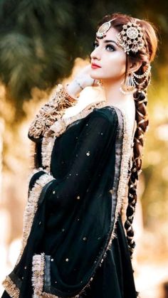 a woman with long braids wearing a black dress and headdress is posing for the camera