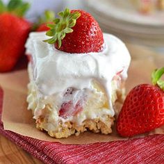 a close up of a piece of cake with strawberries on top and whipped cream