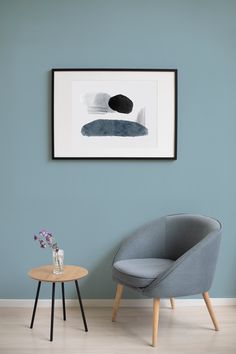 a chair and table in front of a blue wall with a painting on the wall