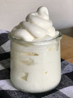 a glass jar filled with whipped cream on top of a checkered table cloth