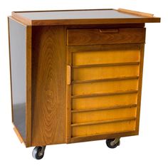 a small wooden cabinet with wheels on it's front and side doors open to reveal drawers