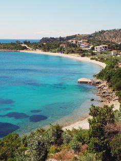 the beach is clear and blue with lots of trees in front of it, as well as houses