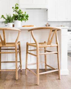 two wooden chairs sitting next to each other on top of a hard wood floored kitchen