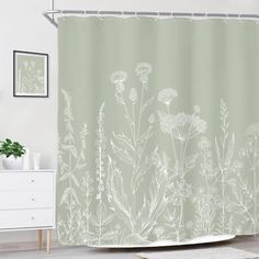 a shower curtain with white flowers and plants on it in front of a wall mounted mirror