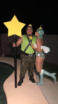 a man and woman dressed up as tinkerbells pose with a star sign