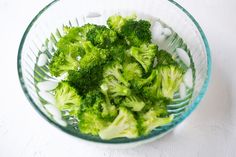 a bowl filled with broccoli on top of a white table