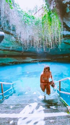 a woman standing on a dock next to a body of water with algae hanging from the ceiling