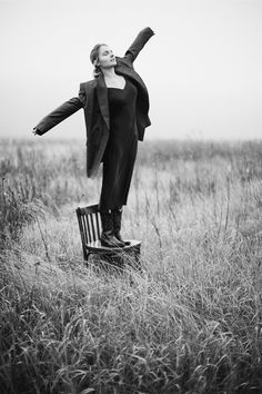 a woman standing on top of a chair in a field