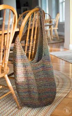 a crocheted bag sitting on top of a rug next to a wooden table