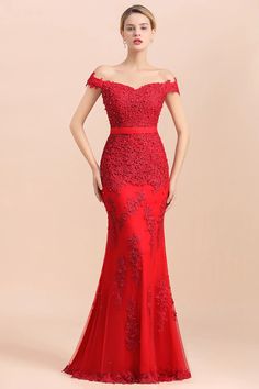 a woman in a red evening gown with an off the shoulder neckline and sleeves