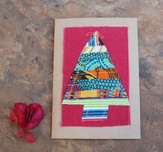 a card with a colorful triangle on it and a red flower next to the card