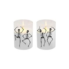 two candles with skeletons on them sitting next to each other in front of a white background