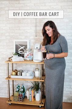 a pregnant woman standing in front of a coffee bar cart holding a glass of wine