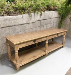 a wooden table sitting next to a wall with plants growing on the top and bottom