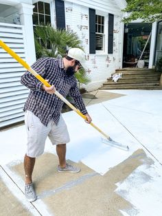 a man with a broom in his hand is standing on the sidewalk and cleaning it