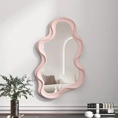 a mirror that is on the wall next to a vase with a plant in it