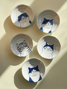 four bowls with cats painted on them are arranged in the shape of a circle,