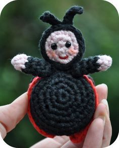 a small crocheted black and red toy with a creepy face on it's head