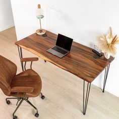 a laptop computer sitting on top of a wooden desk next to a brown office chair