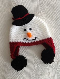 a crocheted snowman hat on top of a white blanket with black feet