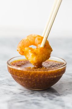 the dipping sauce is ready to be eaten with chopsticks and shrimp rings in it