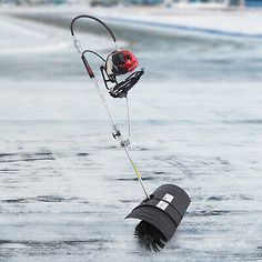 an ice fishing device is hooked up to a pole on the frozen surface with water around it