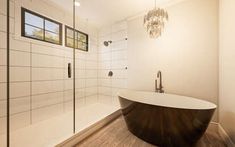 a bath tub sitting next to a shower in a bathroom under a chandelier