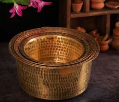 three brass bowls sitting on top of a table next to vases with flowers in them