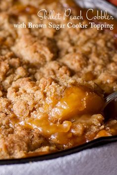 a close up of a pie on a pan with a spoon in it and the words, skillet peach cobbler with brown sugar cookie topping