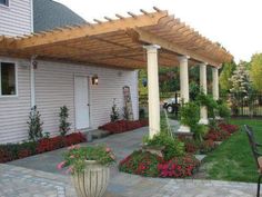 a patio covered in plants and flowers next to a house