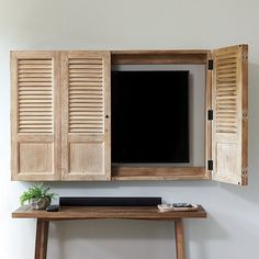 an open wooden window with shutters on the side and a small table underneath it