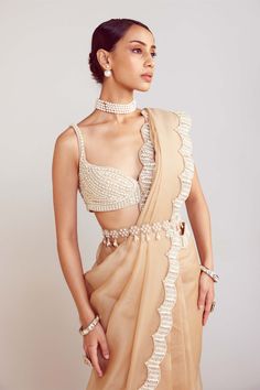 Editor's Note Dazzle in this exquisite beige pearl embellished saree paired with a flattering sweetheart neck blouse. The ethereal combination of delicate pearls and a feminine neckline creates a stunning ensemble that exudes elegance and grace. Perfect for special occasions and celebrations, this ensemble will make you the epitome of timeless beauty. Note: Hanging tassel at the back and belt is not included in the outfit and only for styling purposes Fabric: Blouse: georgette, sari: organza Col Vani Vats, Embellished Saree, Beige Blouse, Backless Blouse, Embellished Blouse, Stylish Sarees, Organza Saree, Lehenga Designs, Saree Look