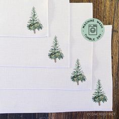 four napkins with trees on them sitting on top of a wooden table next to a rubber stamp