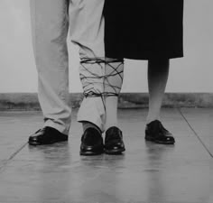 two people standing next to each other with their legs wrapped in strings on the ground