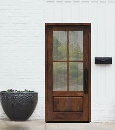 a black planter sitting next to a door on the side of a white building