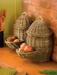 two wicker baskets filled with vegetables sit on a table next to a brick wall