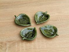 four leaf shaped dishes sitting on top of a wooden table