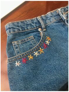 a pair of jeans with embroidered flowers on them