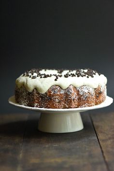 a cake with white frosting and chocolate sprinkles on top sitting on a plate