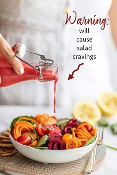 a woman is pouring dressing into a salad