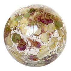 a close up of a glass ball with flowers on it's side and leaves all over the surface